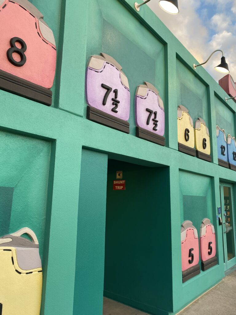 A bright green building decorated to look like a shoe rack at a bowling alley, with shoe sizes on the backs of the shoes.