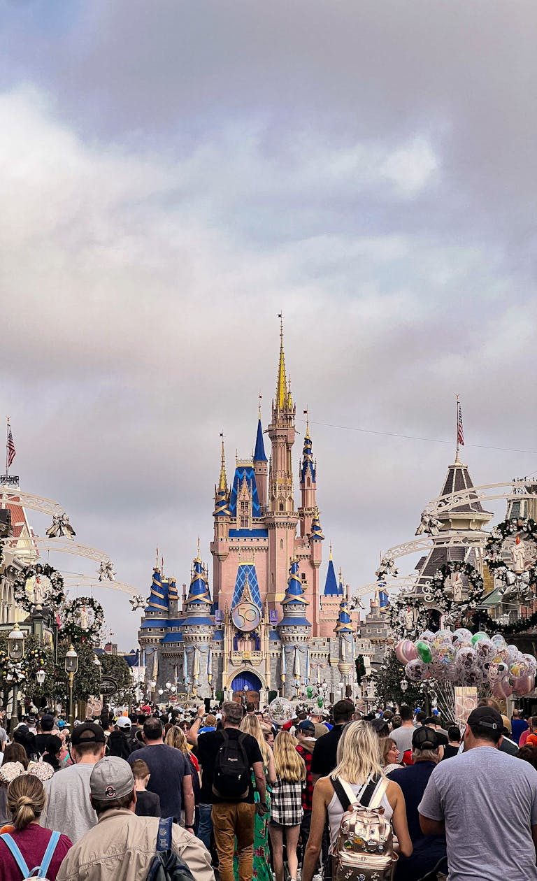 A bustling crowd approaches the iconic Cinderella Castle in Magic Kingdom, Florida.