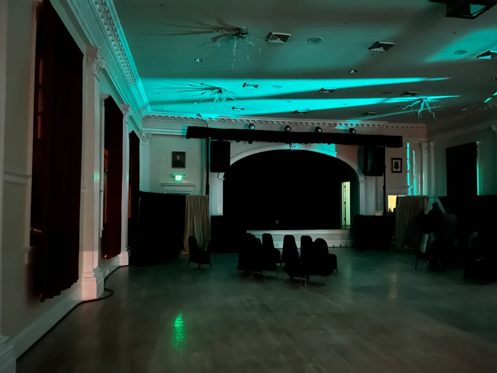 A concert hall with white walls and red curtains framing the stage.