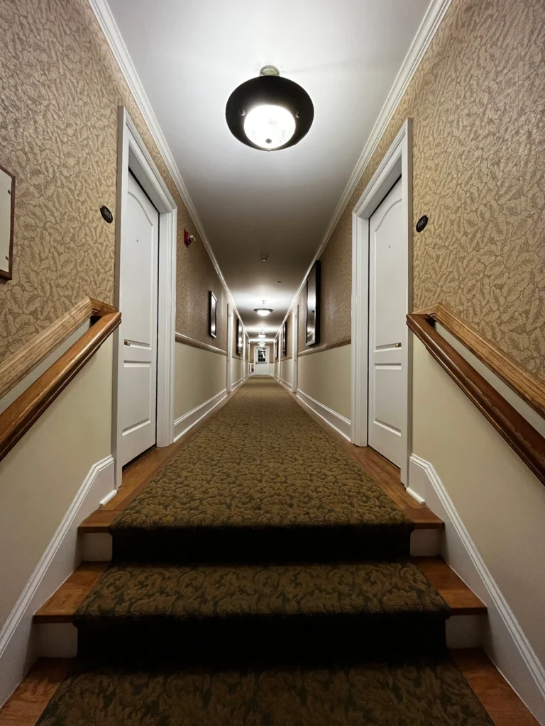 A long narrow hallway in a hotel with white doors leading to guest rooms.