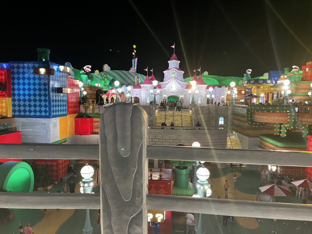 Super Nintendo World at night with bright lights and colors.