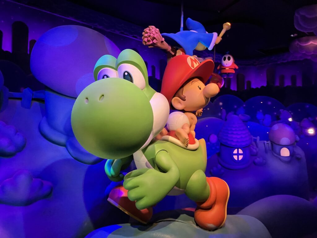 A statue of a green dinosaur (Yoshi) with a baby Mario on its back.