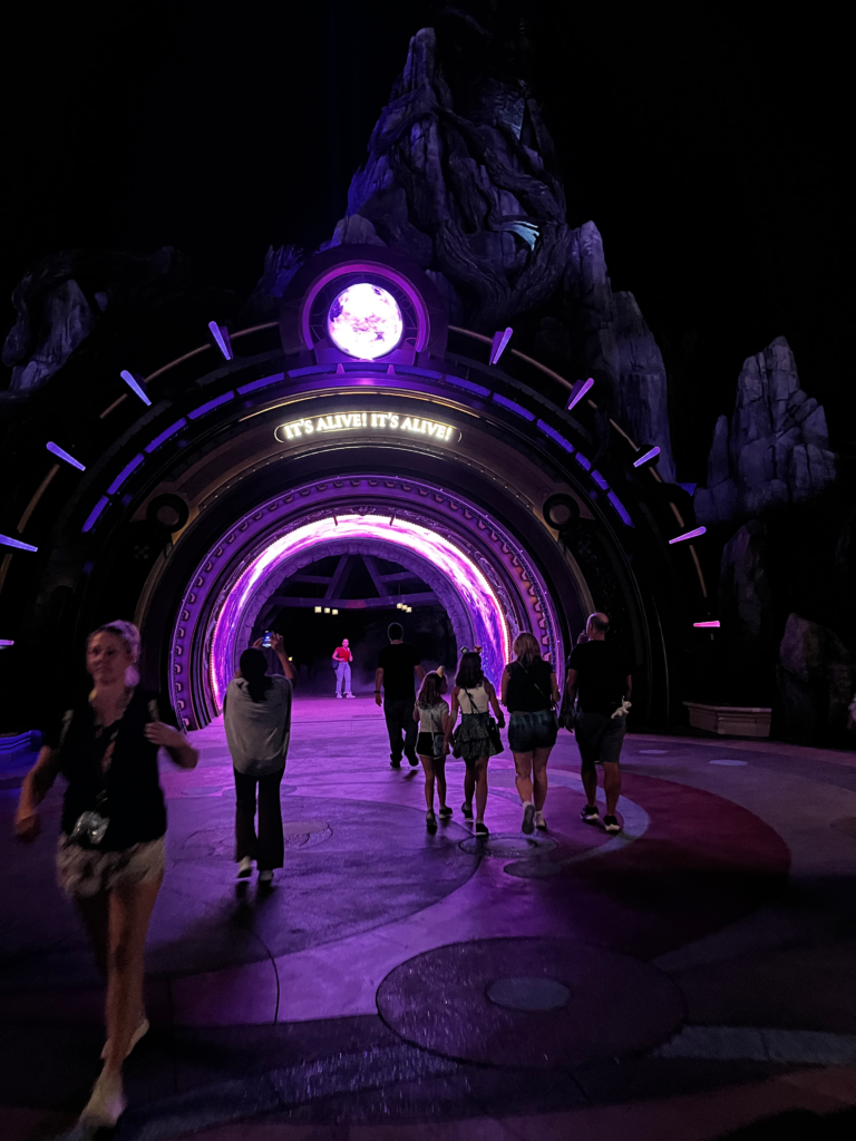 visitors walk through a purple, glowing portal into Dark Universe.