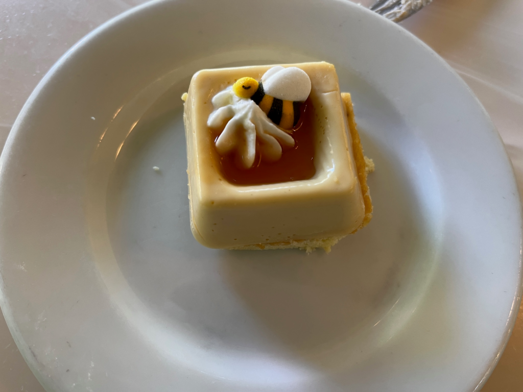A bite-sized square of cheesecake with a bee candy bit on top.